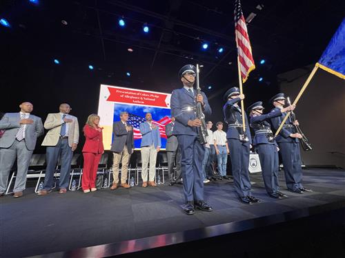board lined up behind color guard standing at attention